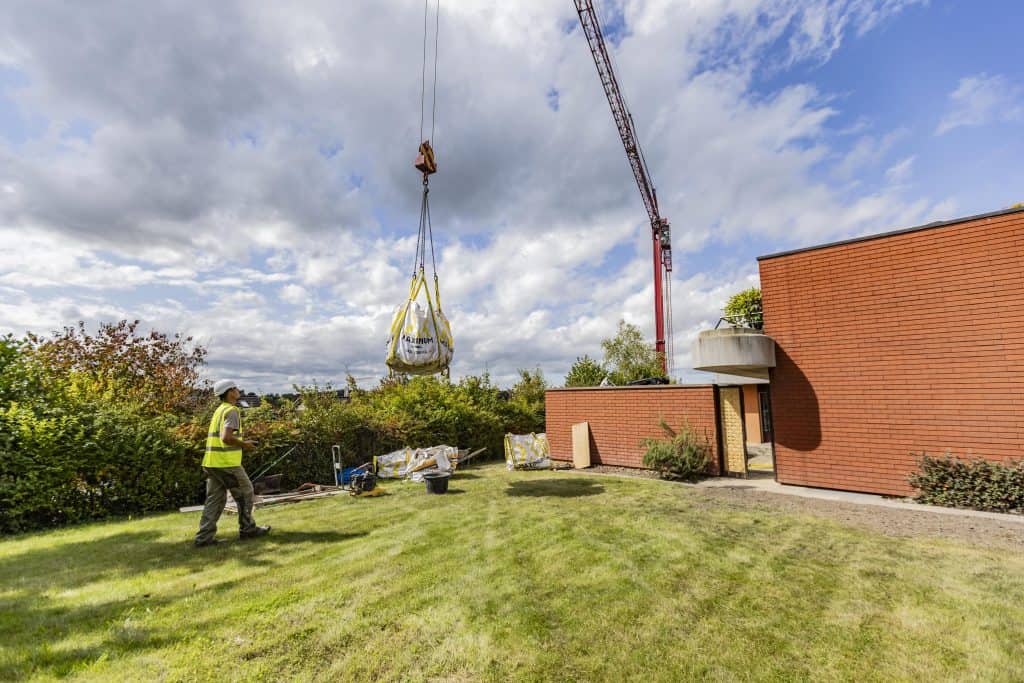 Kran hebt Baumaterialien in einen schwererreichbaren Garten